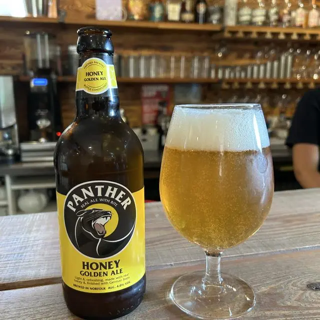 Panther brewery honey poured in to a glass next to the bottle