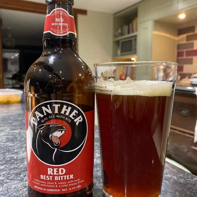 Panther red poured in glass next to bottle